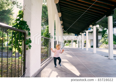 Little girl walks through the long pavilion in the park 83728022
