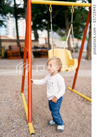 Kid holds the swing with his hand 83728443