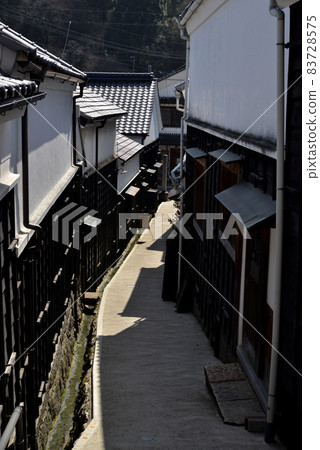 In the old-fashioned townscape, a winding narrow road continues between the white walls. In the old-fashioned townscape, a winding narrow road continues between the white walls. 83728575