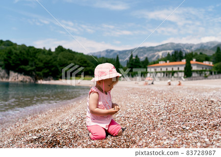 Little girl sitting on her knees on the beach by the water. Villa Milocer 83728987
