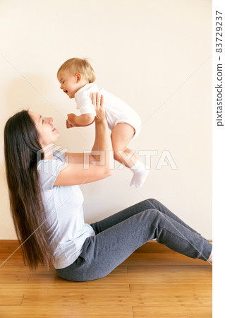 Laughing mother raises a little girl above her head Laughing mother raises a little girl above her head 83729237
