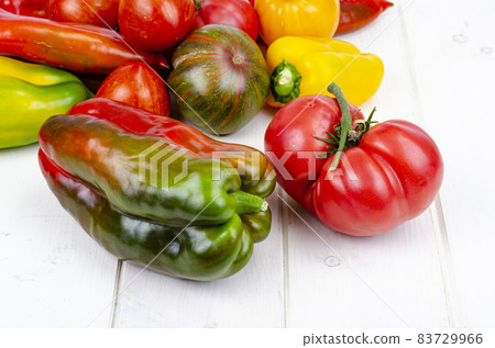 Multicolored sweet peppers and tomatoes on wooden table. Studio Photo. Multicolored sweet peppers and tomatoes on wooden table. Studio Photo. 83729966