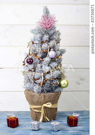 We celebrate Christmas and New Year. Small decorative Christmas tree decorated with balls and toys. Studio Photo. We celebrate Christmas and New Year. Small decorative Christmas tree decorated with balls and toys. Studio Photo. 83730871
