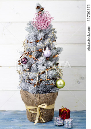 We celebrate Christmas and New Year. Small decorative Christmas tree decorated with balls and toys. Studio Photo. We celebrate Christmas and New Year. Small decorative Christmas tree decorated with balls and toys. Studio Photo. 83730873