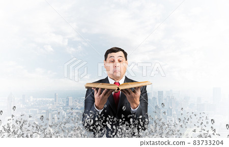 Surprised businessman holding open old book 83733204