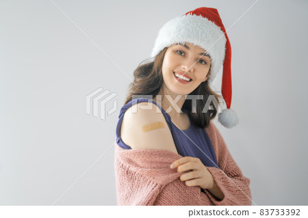 Young woman after vaccination wearing Santa hat 83733392