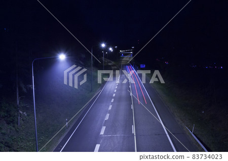 Long exposure photo of traffic with blurred traces from cars at night in Finland, top view. Long exposure photo of traffic with blurred traces from cars at night in Finland, top view. 83734023
