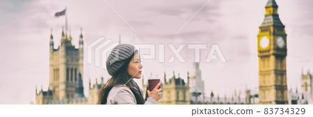 London travel woman drinking coffee cup by Big Ben Westminster in cold morning fall. Asian tourist girl pensive looking at view banner panorama. 83734329