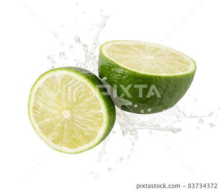 Lime half and a slice are falling on a white background. Isolated Lime half and a slice are falling on a white background. Isolated 83734372