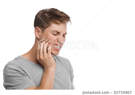 Despaired millennial caucasian attractive male presses his hand to cheek and suffers from toothache 83734867