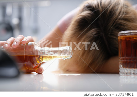 Upset drunk woman with bottle of alcohol, close-up 83734901