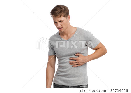 Unhappy sad millennial european attractive man presses his hand to sore spot and suffers from stomach pain Unhappy sad millennial european attractive man presses his hand to sore spot and suffers from stomach pain 83734936