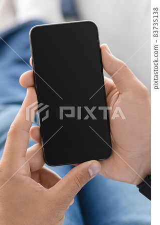 Unrecognizable millennial man check mail, social networks on smartphone with empty screen, at home 83735138