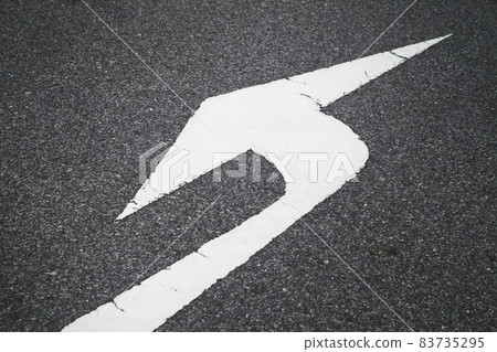 white direction arrow sign paint on black asphalt road surface. 83735295