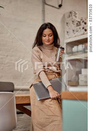 Young female with laptop and hot drink Young female with laptop and hot drink 83735610