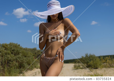 Topless woman covering breast on beach 83735814