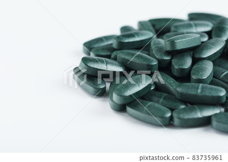 Pills with Vitamins and spirulina on a white background. 83735961