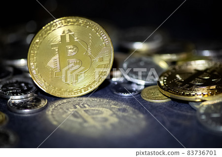 Golden bitcoin cryptocurrency reflects in light on dark surface, metallic coins scattering on backgrounnd 83736701