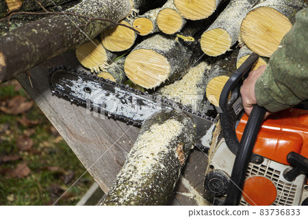 Close-up professional chainsaw blade cutting log of wood. Close-up professional chainsaw blade cutting log of wood. 83736833