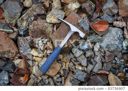 Steel geologist rock pick over brown and grey rocks in chromite mining area in Troodos mountains, Cyprus 83736907