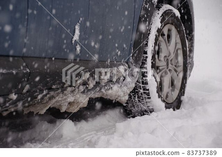 Front tires and lower doors of cars traveling on snowy roads 83737389