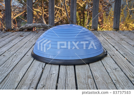 Balance training ball on wooden deck 83737583