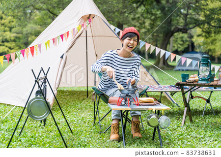 Young woman baking pancakes at a campsite 83738631