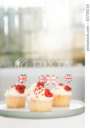 Cupcake with British Union jack flag and poppy flower. Remembrance Day. Vertical card. Selective focus, copy space. 83739216