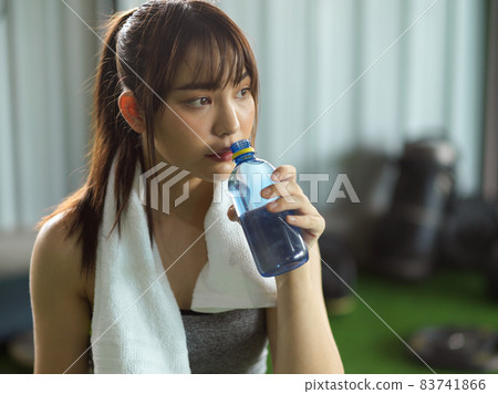 Tired sporty girl taking a rest and drinking a water Tired sporty girl taking a rest and drinking a water 83741866