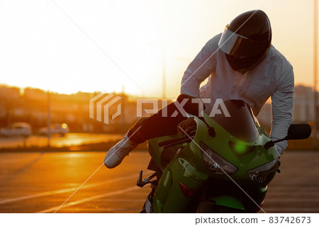Cool man on motorcycle against sundown sky Cool man on motorcycle against sundown sky 83742673