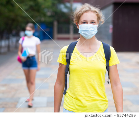 Girl student in protective mask walks down street to college Girl student in protective mask walks down street to college 83744289
