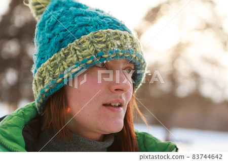 portrait of a beautiful girl in a hat and scarf on the background in the cold season. girl walking down the street portrait of a beautiful girl in a hat and scarf on the background in the cold season. girl walking down the street 83744642