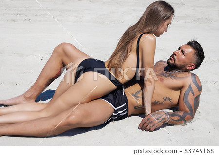 Hot couple lying on sandy seashore 83745168