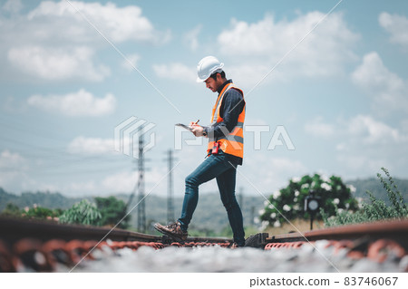 Engineer railway under checking construction process train testing and checking railway work on railroad station with radio communication .Engineer wearing safety uniform and safety helmet in work. Engineer railway under checking construction process train testing and checking railway work on railroad station with radio communication .Engineer wearing safety uniform and safety helmet in work. 83746067