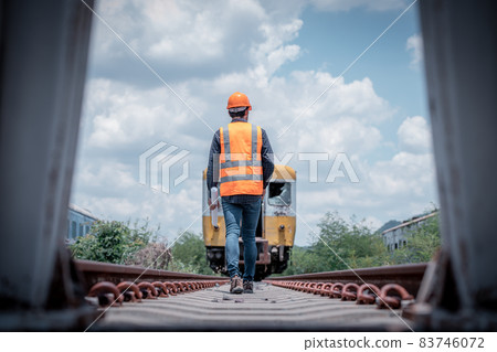 Engineer railway under  checking construction process train testing and checking railway work on railroad station with radio communication .Engineer wearing safety uniform and safety helmet in work. 83746072