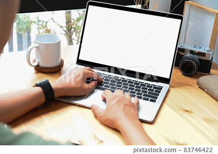 View over shoulder young man working online with laptop computer at home. 83746422