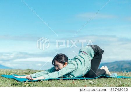 Woman doing yoga outdoors (cat pose) 83748030