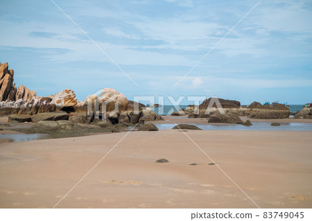 Scenic view of the beach with big stones. Boats sailing on the sea. View of the bay with crystal water. Colourful vietnamese fishing boats. Scenic view of the beach with big stones. Boats sailing on the sea. View of the bay with crystal water. Colourful vietnamese fishing boats. 83749045