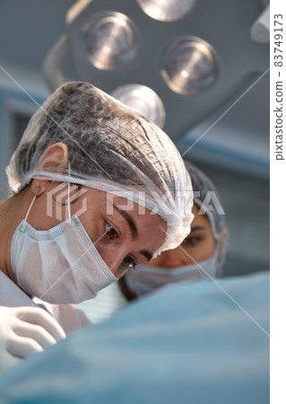 Close up of the face of a patient who is undergoing blepharoplasty. The surgeon cuts the eyelid and performs manipulations using medical instruments 83749173