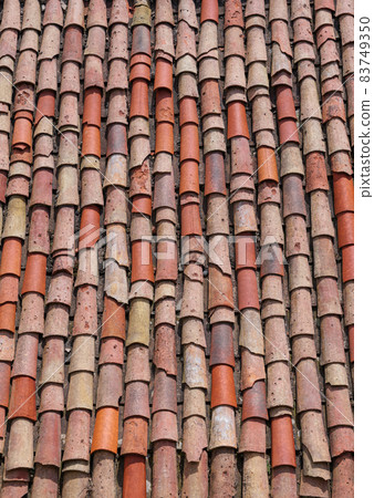 Vertical close-up of old weathered red and orange roof tiles. Vertical close-up of old weathered red and orange roof tiles. 83749350