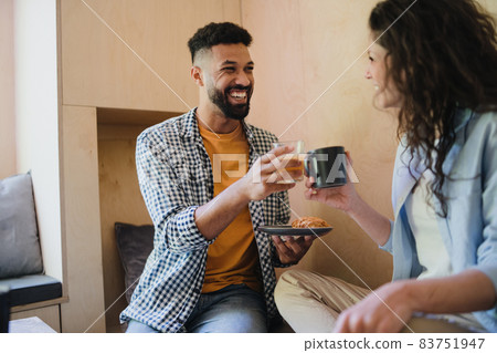 Happy couple sitting, resting and drinking coffee indoors in a tree house, weekend away. 83751947