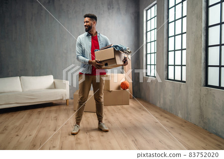 Happy young man holding packing boxes moving home, new living concept. 83752020