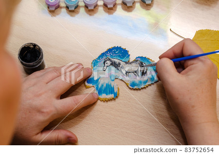 Modern Art. Woman painting a horse on a dried fallen tree leaf. Modern Art. Woman painting a horse on a dried fallen tree leaf. 83752654