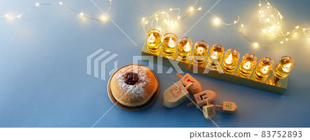 Jewish holiday Hanukkah background with menorah- traditional candelabra, spinning top and doughnut on blue background 83752893