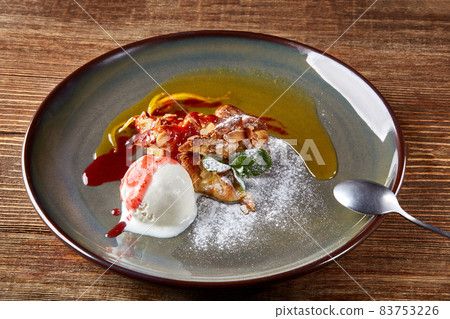 Apple strudel with mint and ball of vanilla ice cream on dish on a wooden background. All sprinkled with powdered sugar. 83753226