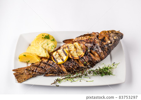 Grilled carp fish with rosemary potatoes and lemon, close up 83753297