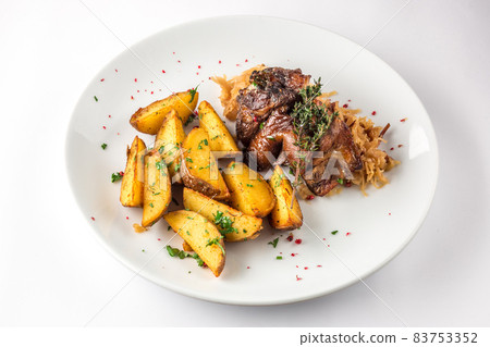 Delicious grilled duck wings with potatoes and stewed cabbage on a white plate 83753352