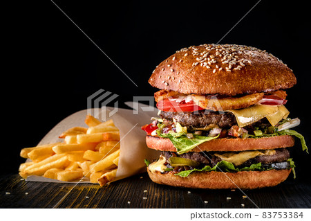Craft beef burger and french fries on wooden table isolated on black background. Craft beef burger and french fries on wooden table isolated on black background. 83753384
