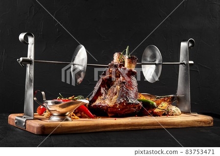 Roasted pork knuckle eisbein with braised boiled cabbage, potatoes, chili peppers and mustard on wooden cutting board, on a black background Roasted pork knuckle eisbein with braised boiled cabbage, potatoes, chili peppers and mustard on wooden cutting board, on a black background 83753471