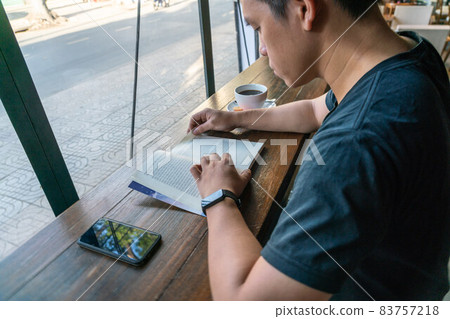 Young male student reading book in a cafe Young male student reading book in a cafe 83757218